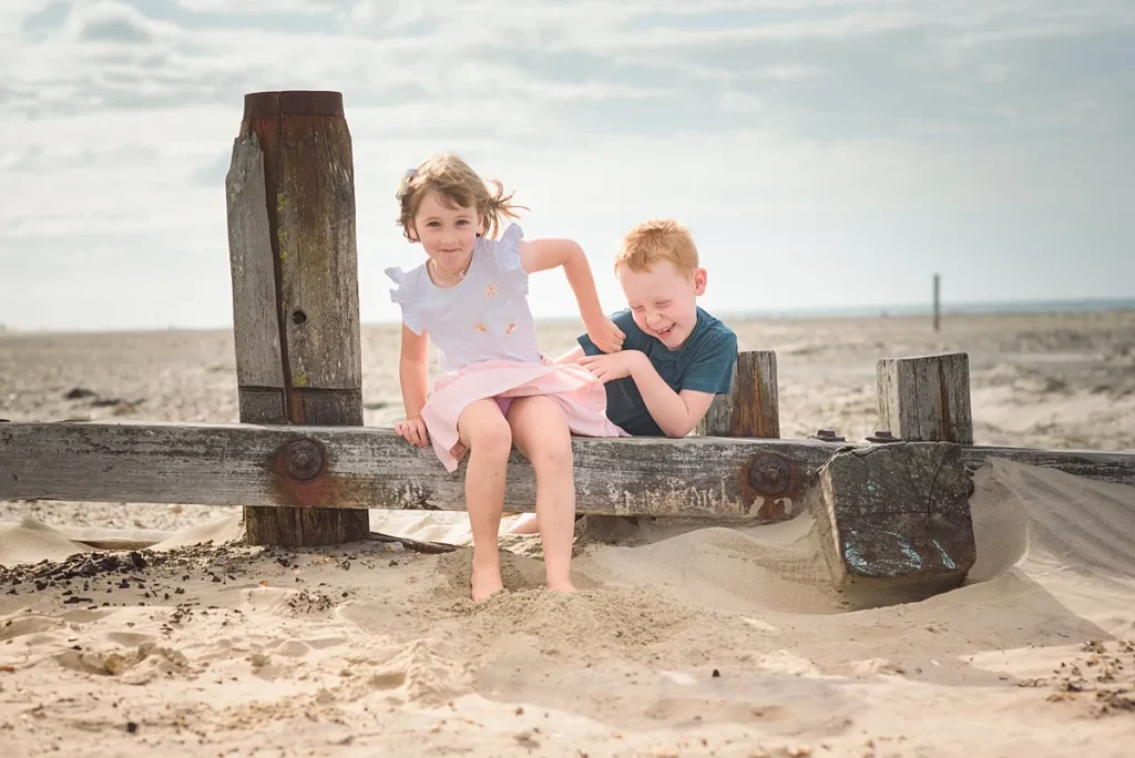 Beach portrait of a brother and sister playing on the sand. Captured at West Wittering beach by outdoor family photographer Maria Cristina Licata