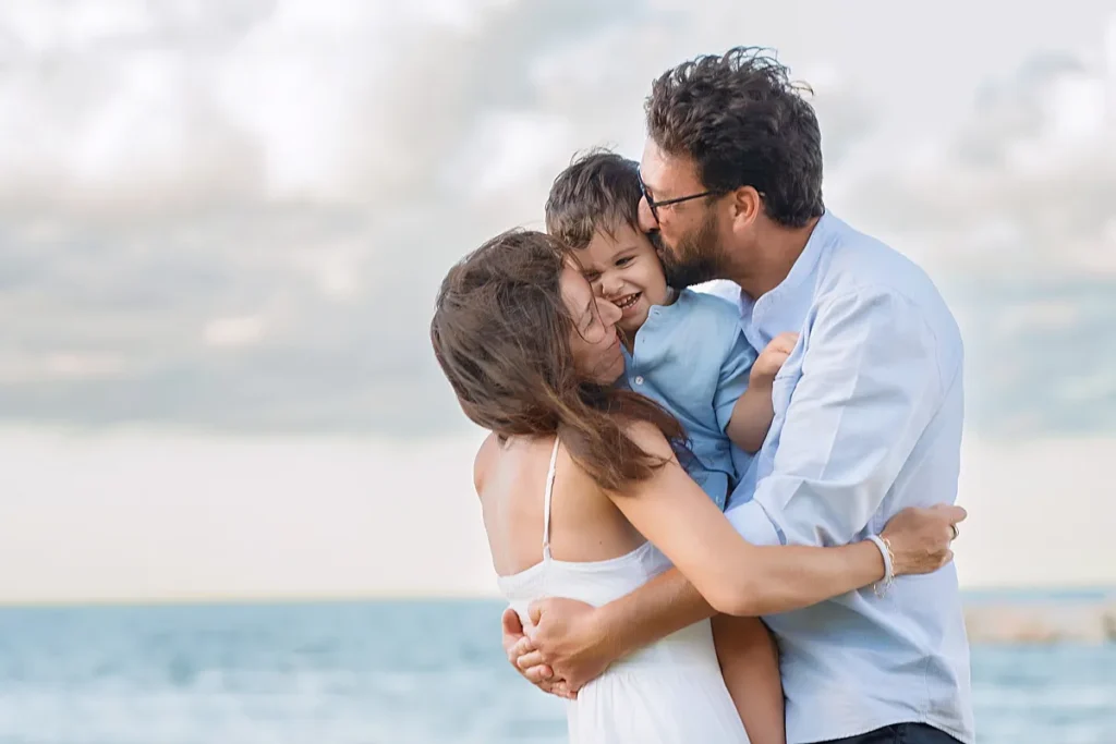 Parents lifting their child in the air with the ocean in the background during a family photoshoot in Sicily by family photographer Maria Cristina Licata.