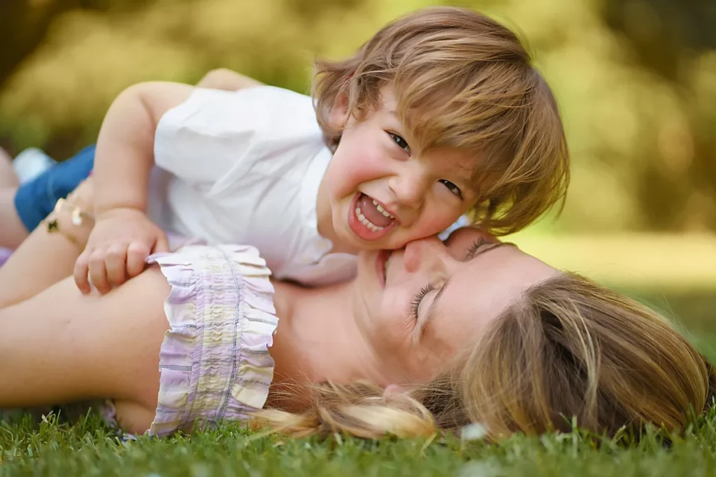 Mother cuddles toddler son while laying on the grass during a relaxed family photo session near Reading