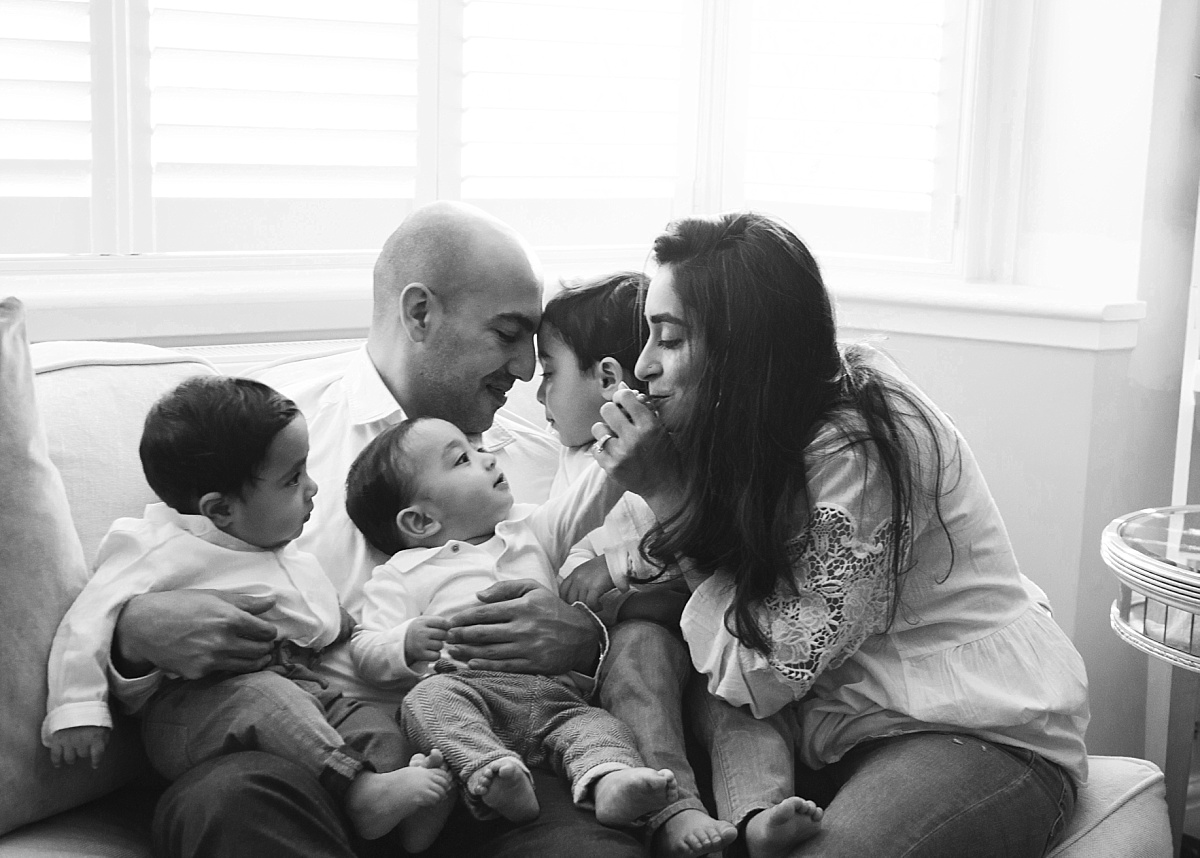 parents and siblings playing together in their living room during an in-home family photoshoot.