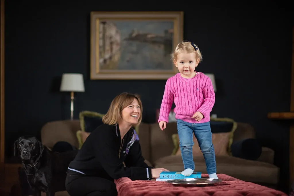 Young girl playing in elegant Cotswolds home with her laughing mum. Captured by Berkshire family photographer Maria Cristina Licata