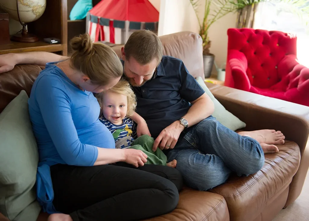 Family cuddling on the sofa at their home in Surrey, captured naturally by Hampshire family photographer Maria Cristina Licata.