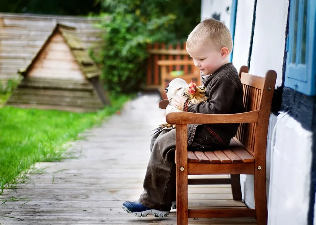 Portrait of a young boy holding his pet chicken in his home garden in Andover, Hampshire. captured by Hampshire family photographer Maria Cristina Licata
