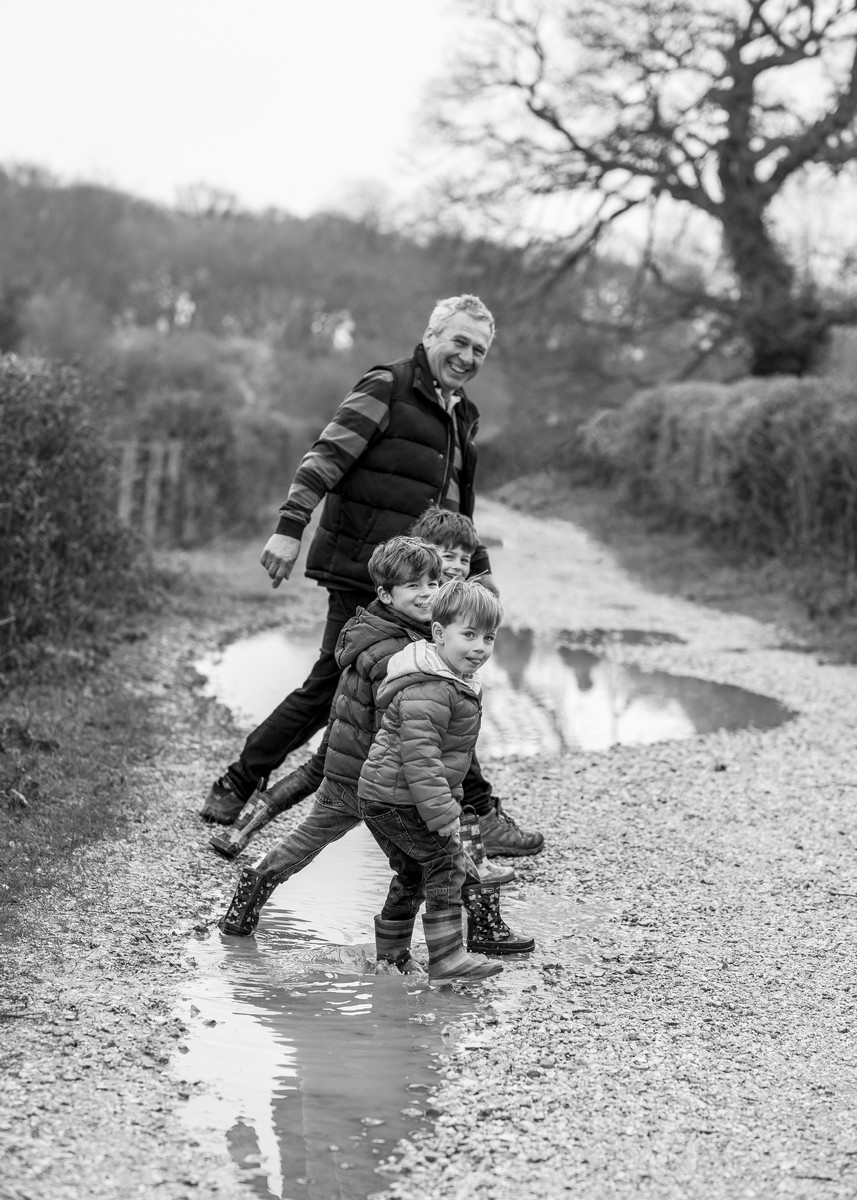 granddad playing in puddles with grandsons during a wintery outdoor photoshoot