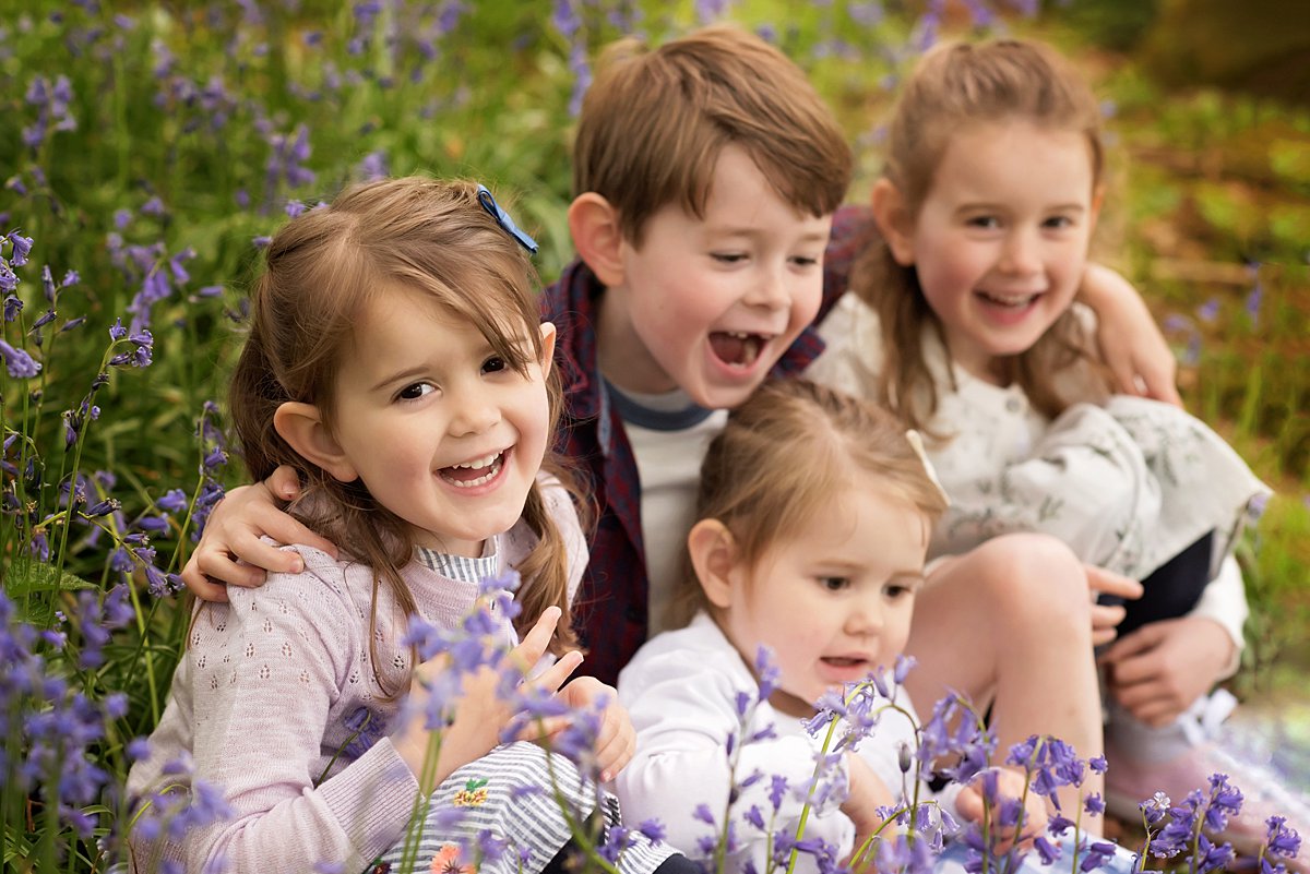 Group of sibling sitting together in a patch of bluebells during a spring family shoot