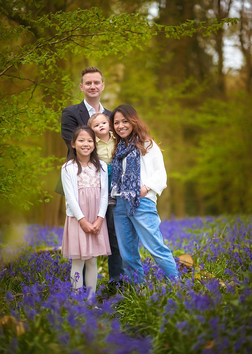 Informal spring family portrait taken by a professional photographer in a bluebells wood