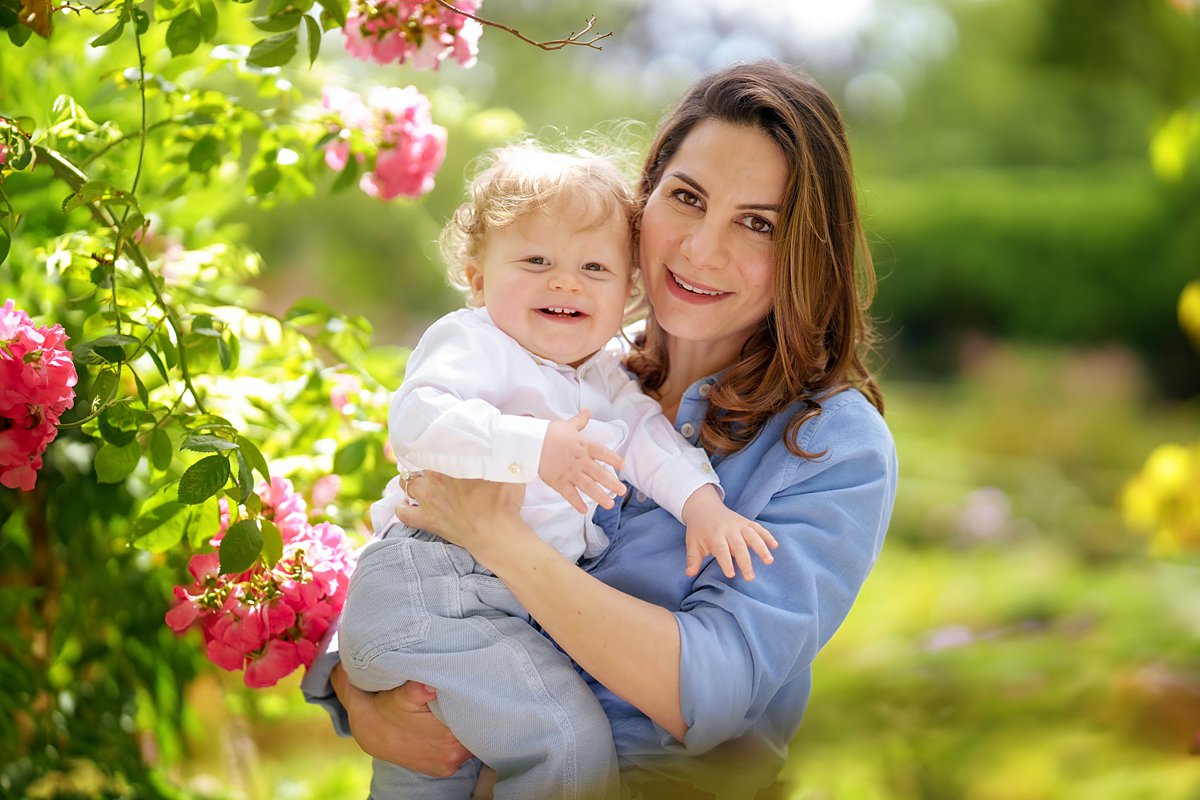 summer-family-photoshoot_0086 Loving mother holding a happy baby amongst blooming pink flowers in a garden during an outdoor portrait session in Berkshire – natural family photography by Maria Cristina Licata.