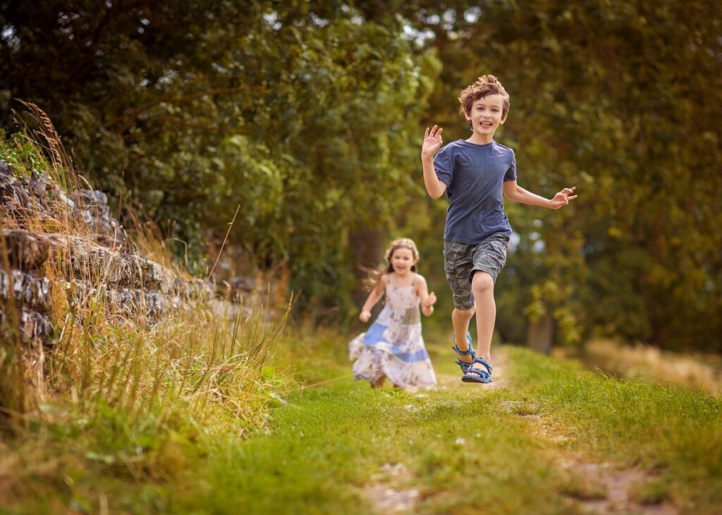 Candid portrait of siblings running along the ancient walls of Silchester, near Reading, by a Reading family photographer