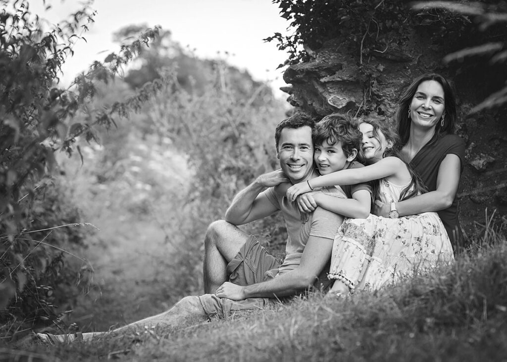 Black and white portrait of a family sitting by an ancient wall at Silchester, near Reading, by a Reading family photographer