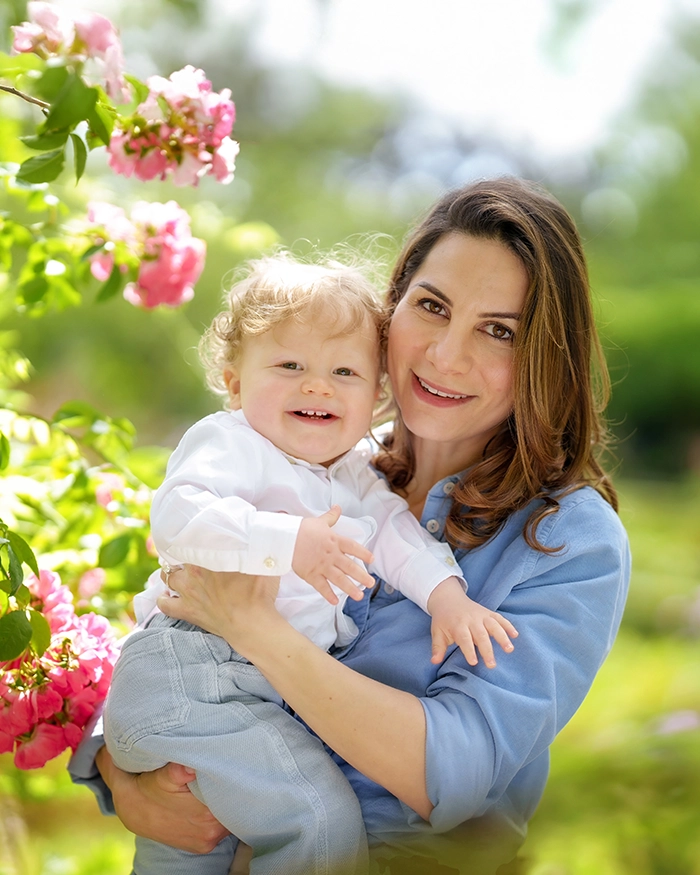 photo-sessions-info-spring natural family portrait of mum and baby boy by a bush of pink blossom, captured by Hampshire family photographer Maria Cristina Licata