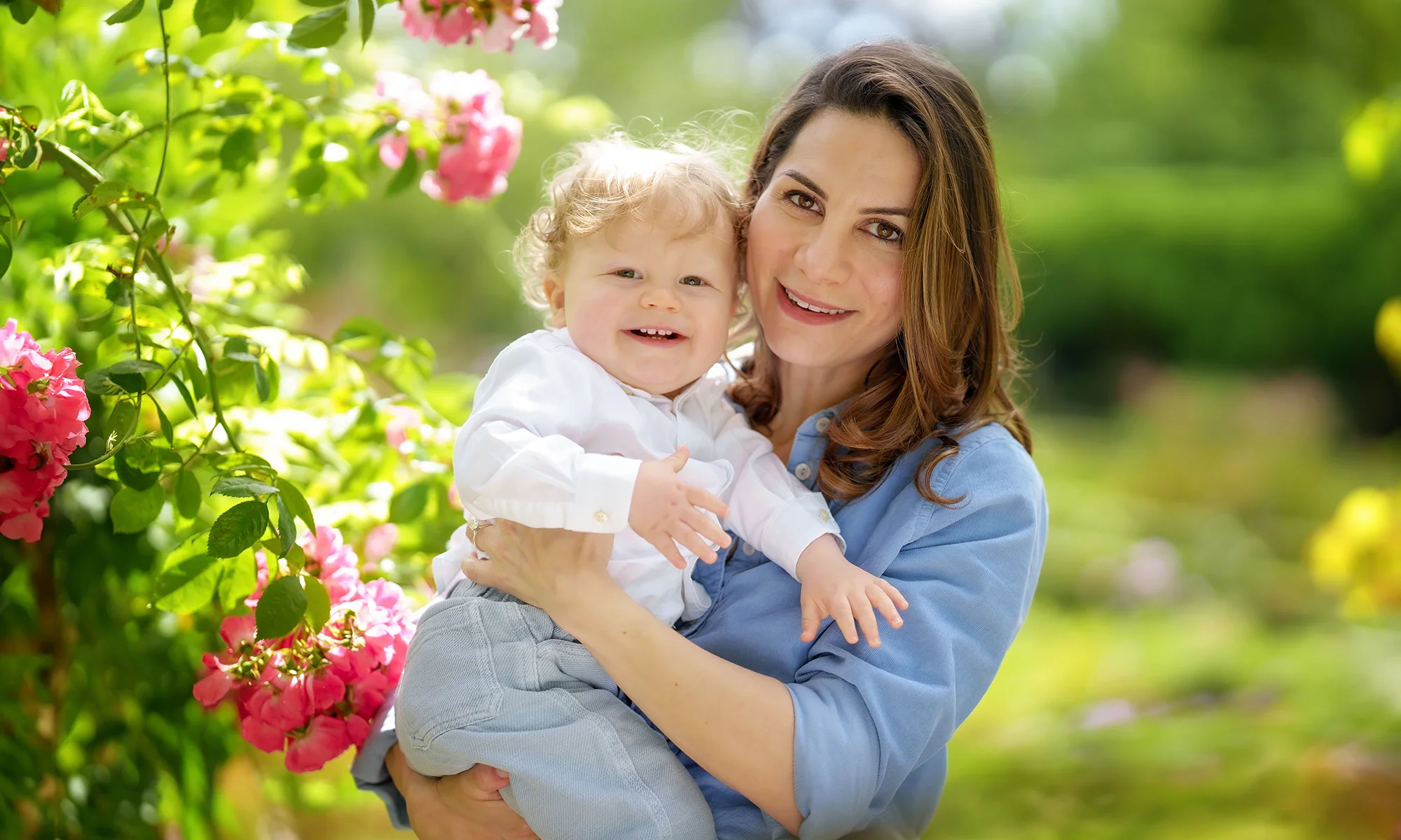 family-photograhy-banner-spring2 happy portrait of mum and dad swinging toddler boy while walking in a London park on a summery sunny day