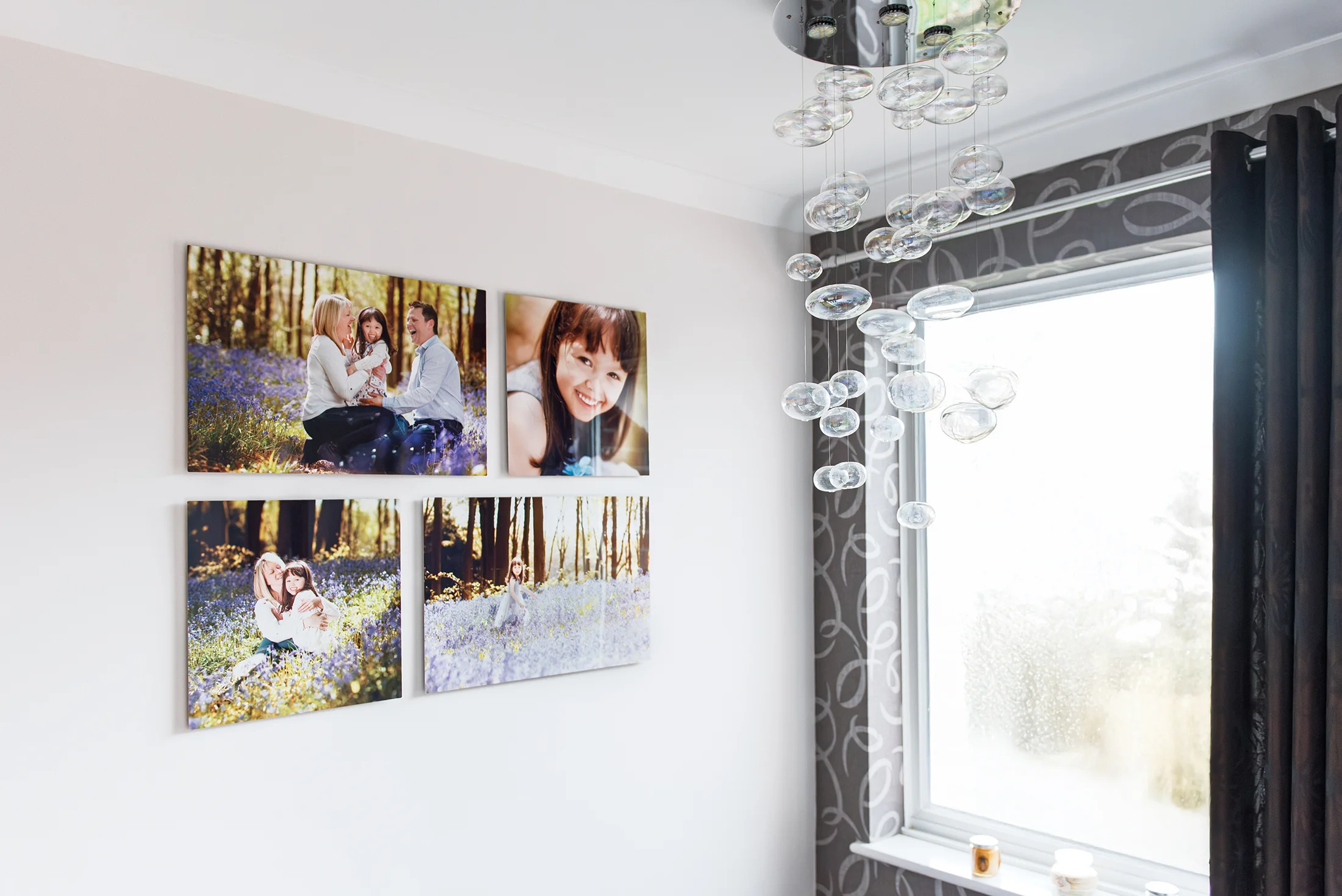 a gallery of four large metallic panel portraits hanging on the walls of a home staircase. 