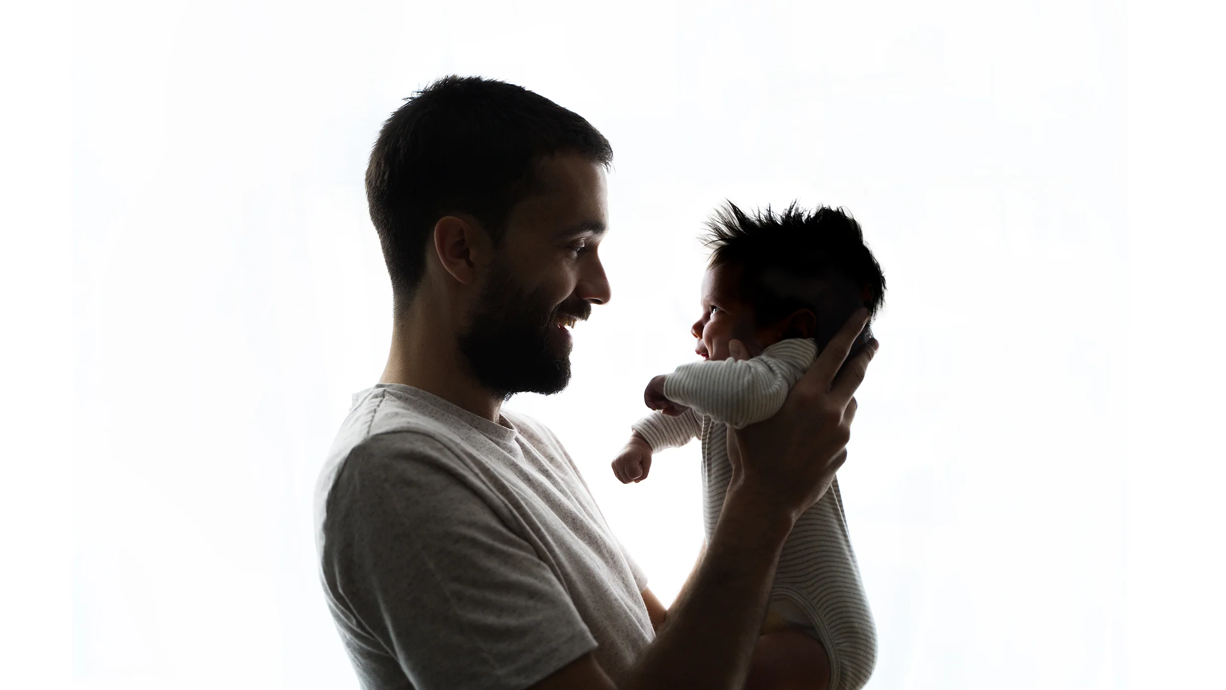 newborn-photography-daddy Father lovingly holding newborn baby during family newborn photoshoot at home in London