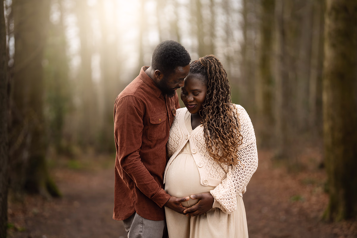outdoor maternity portrait of couple in a woodland location. Dad holding Mum's bump lovingly. Natural pregnancy portrait by Maria Cristina Licata