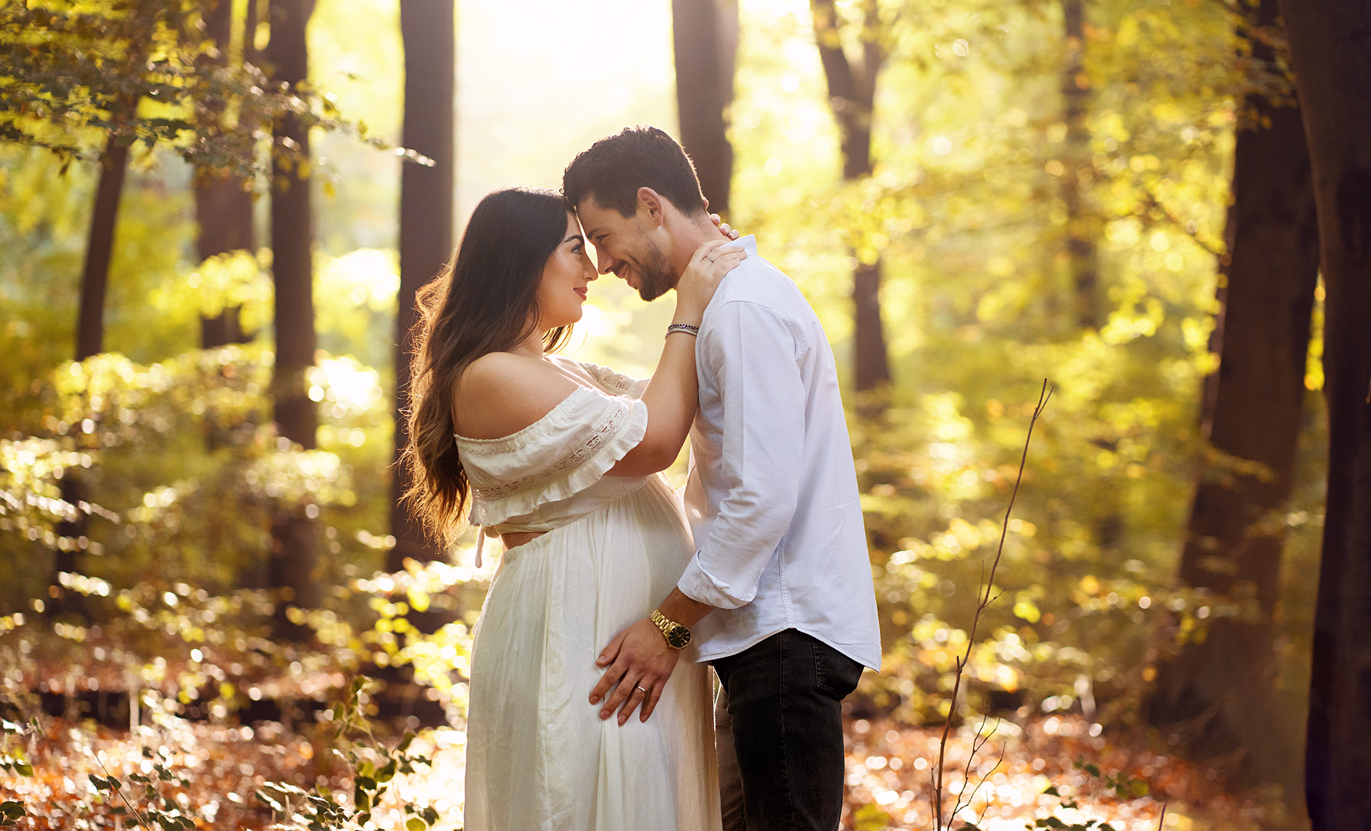 A maternity portrait of a young couple lovingly holding each other. Photographed in woodlands in Hampshire by family photographer Maria Cristina Licata